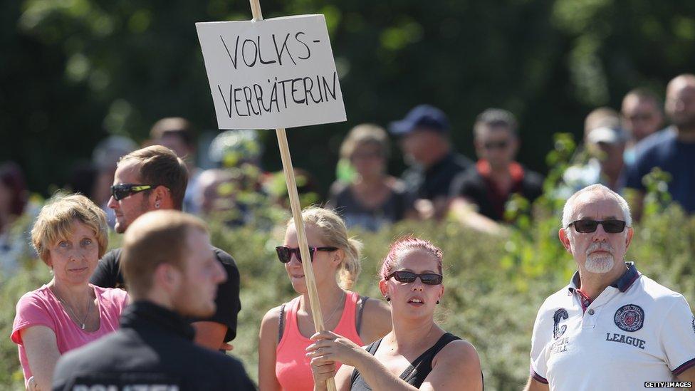 An onlooker holds a sign that reads "Nation Traitor" during a visit by German Chancellor Angela Merkel to the asylum shelter in Heidenau