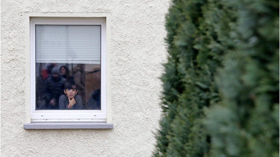 Refugee boy Ramzi Khatoum looks out of the window of a refugee shelter in Clausnitz, eastern Germany, as politicians and journalists visit the home on February 22, 2016.