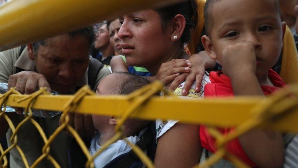 A family in the migrant caravan waits at a gate separating Guatemala from Mexico on 19 October 2018 in Ciudad Tecun Uman, Guatemala