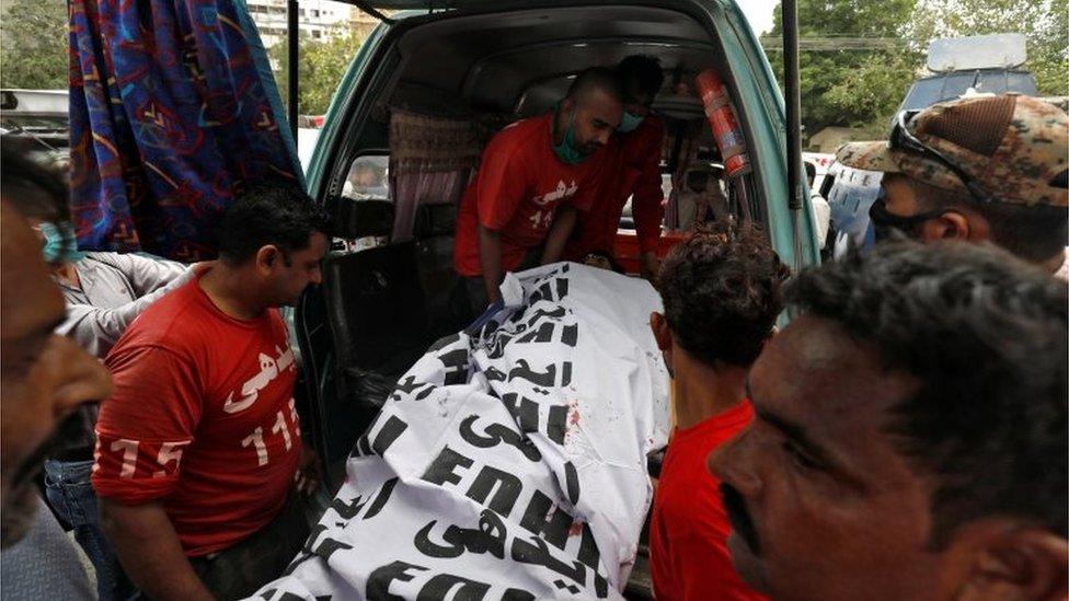 The covered body of a suspected attacker is removed at the site of an attack outside Pakistan Stock Exchange in Karachi June 29, 2020.