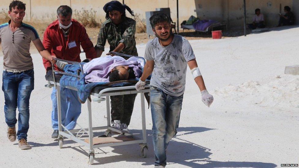 An injured person is stretchered into Emel Kobane Hospital on 25 June 2015