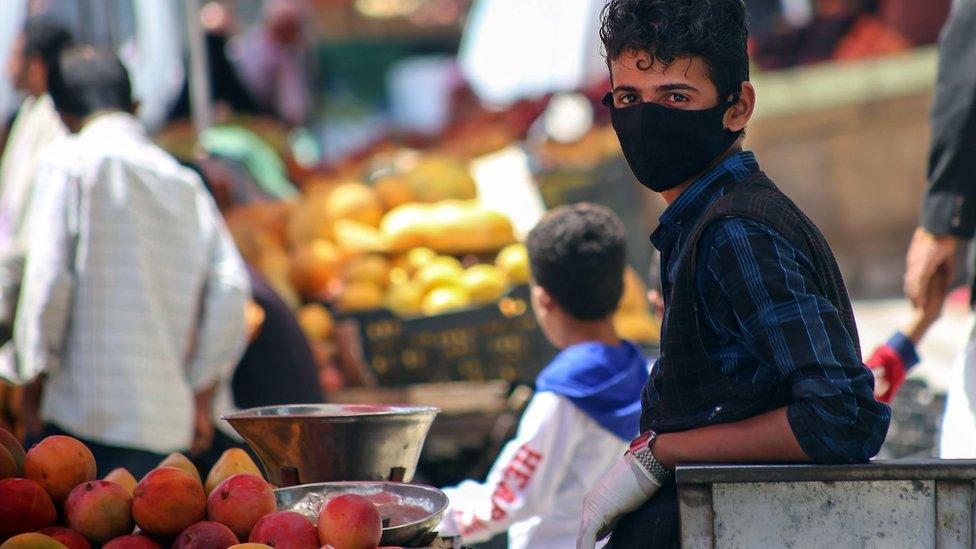 A youth waring a face mask sells fruit at a market in Taiz, Yemen (1 June 2020)