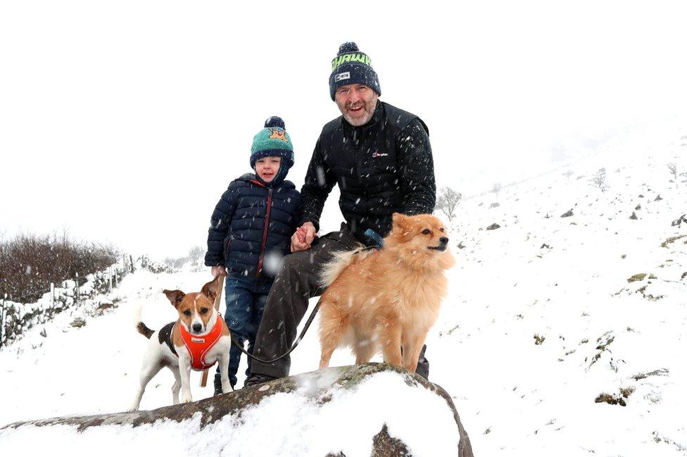 A father, his son and their two dogs walking in the snow on Slemish Mountain