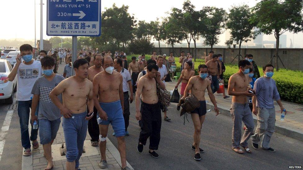 Tianjin residents walk through the streets after two massive explosions