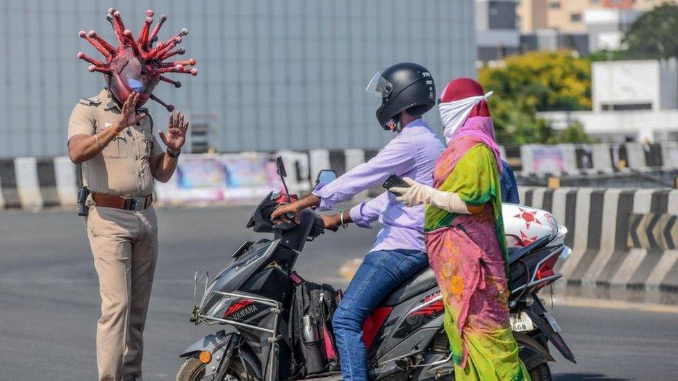 Police inspector Rajesh Babu (left) wearing a coronavirus-themed helmet speaks to motorists during a government-imposed nationwide lockdown as a preventive measure against the COVID-19 coronavirus in Chennai on 28 March 2020