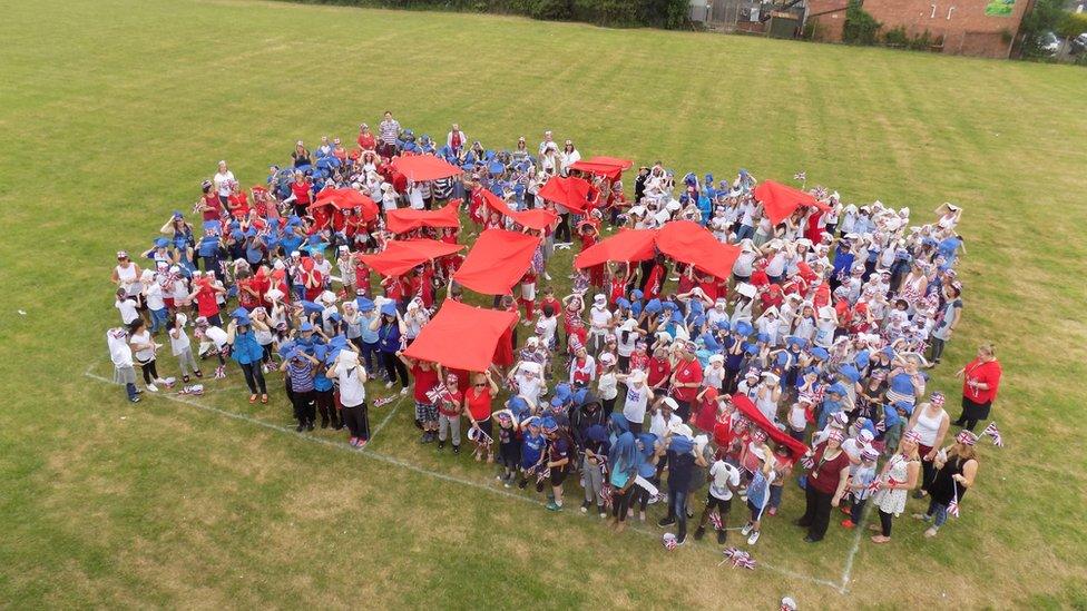 Tom Barton a year 6 teacher at Broadmeadow Junior School in Kings Norton, Birmingham UK, designed the Union Jack flag on the field and then had the children come in to school wearing either red, white or blue to create the flag. Credit: Tom Barton