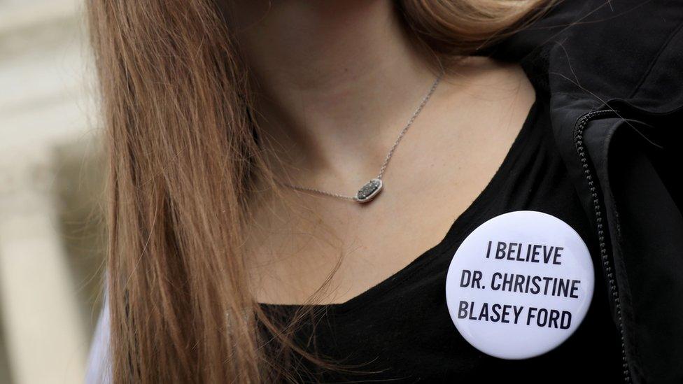 A woman wears a 'I believe Dr Christine Blasey Ford' badge