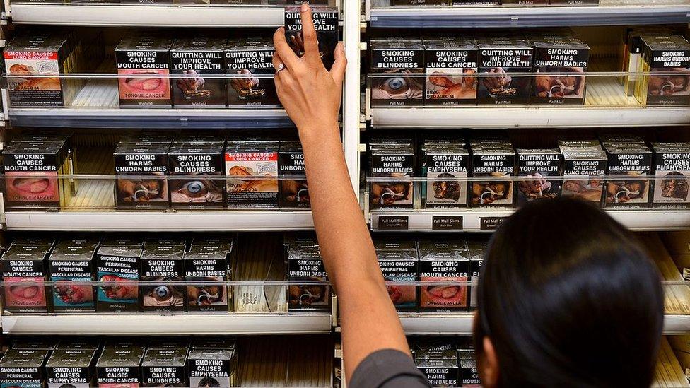 An employee in a shop in Australia selects a package of cigarettes