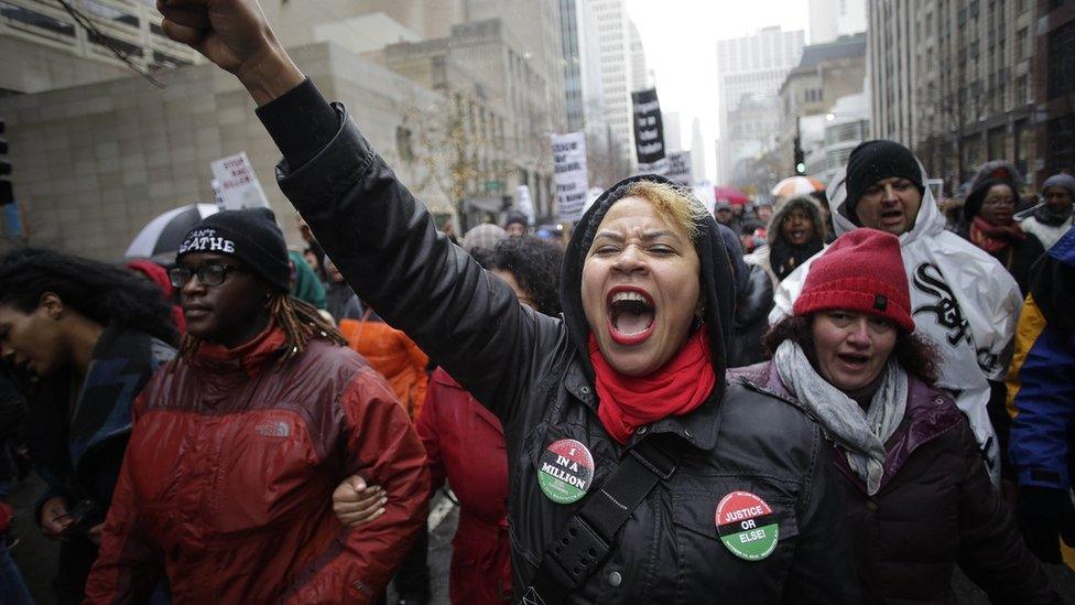 A woman throws her fist in the air as she leads a group of protesters