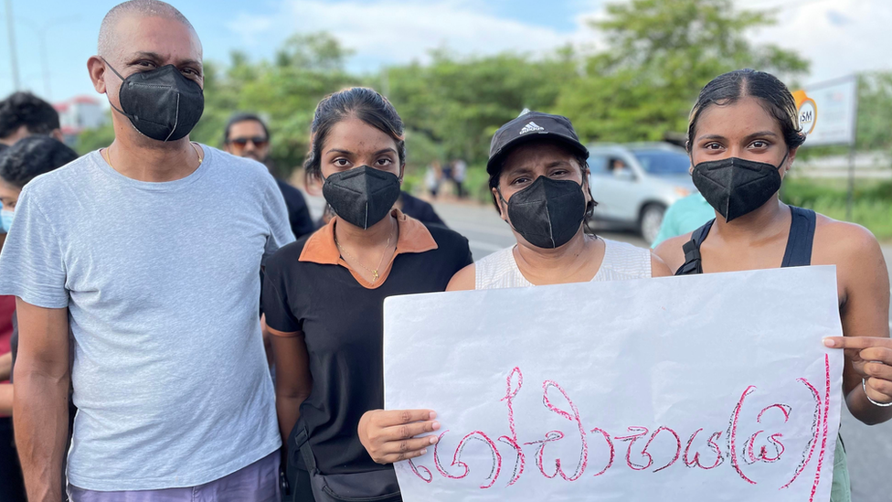 Nadhie Wandurgala with her family holding a sign reading "Go Gota Go"