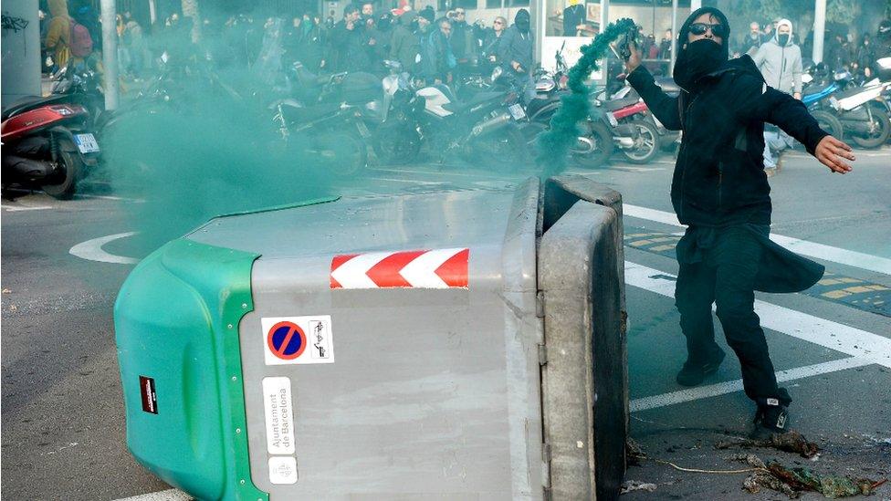 A protester throws a smoke bomb towards police during scuffles at a Catalan pro-independence demonstration in Barcelona on December 21, 2018