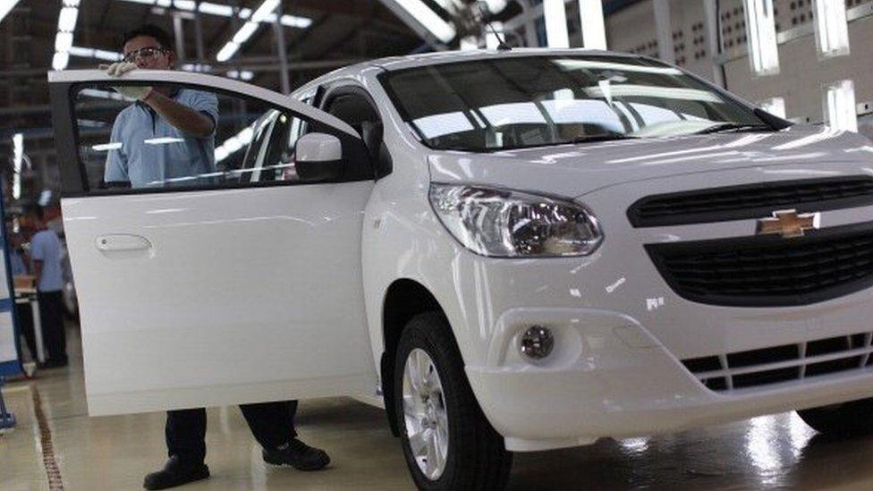 A GM plant worker next to a car being built