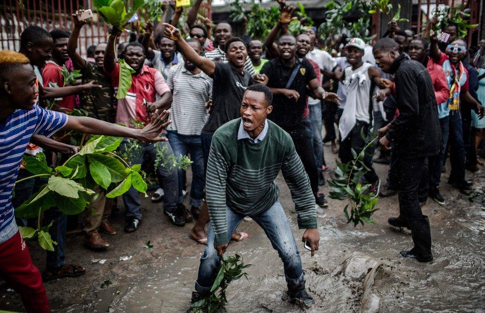 Protesters waiting to cast their ballot, demonstrate outside the College St Raphael polling station, in Kinshasa, on December 30, 2018 while DRC"s electoral commission president arrives for the DR Congo's general elections