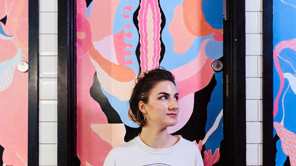 Oliwia Bober standing in front of one of her pieces of art.