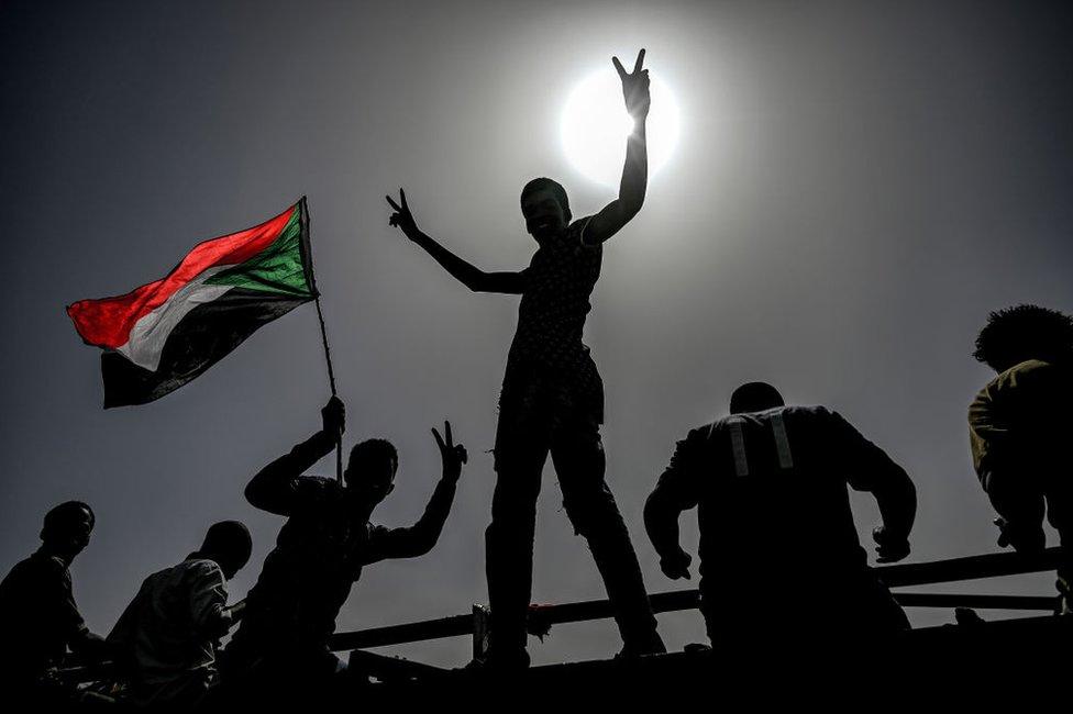 Sudanese protestors wave flags and flash victory signs as they continue to protest outside the army complex in the capital Khartoum on 17 April 2019.