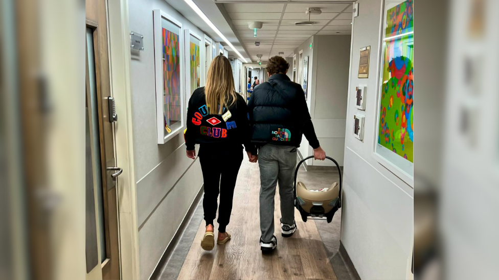 Olly Murs, who is holding a car seat with the baby inside, walks with Amelia