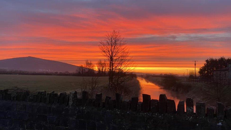 A sunrise above a river with a hill in the background in Loxton