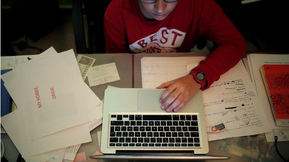 A boy uses a laptop as he does his homework at his home in Ronda, southern Spain,