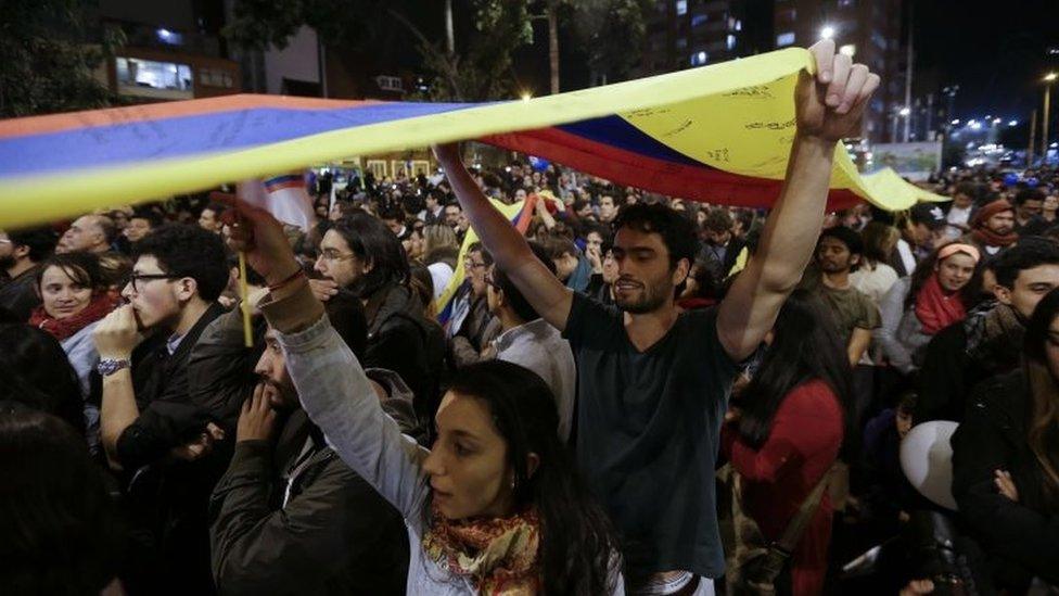 People celebrate the announcement from Havana, Cuba, that delegates of Colombia's government and leaders of the Revolutionary Armed Forces of Colombia reached a peace accord to end their half-century civil war, in Bogota, Colombia, Wednesday, Aug. 24, 2016.