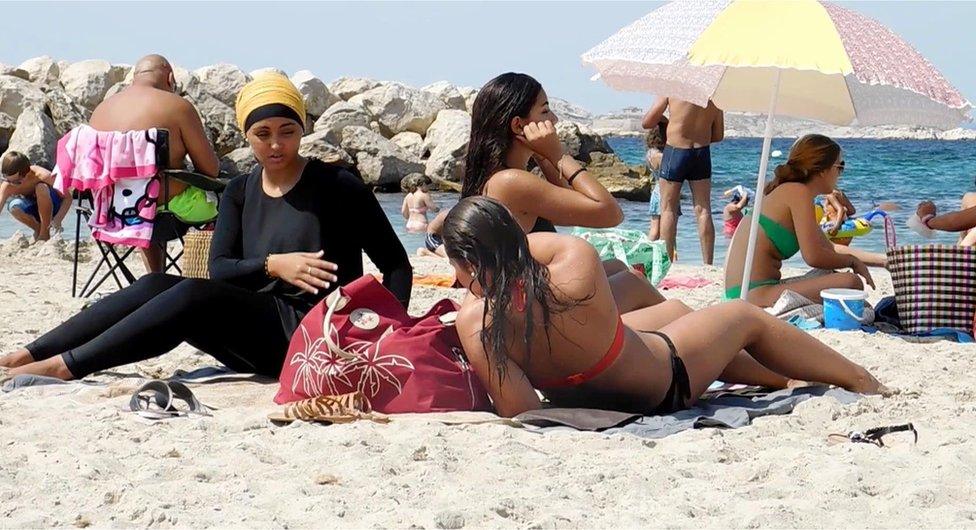 Nesrine Kenza, who says she is happy to be free to wear a burkini, and two unidentified friends rest on the beach in Marseille, France, 29 August