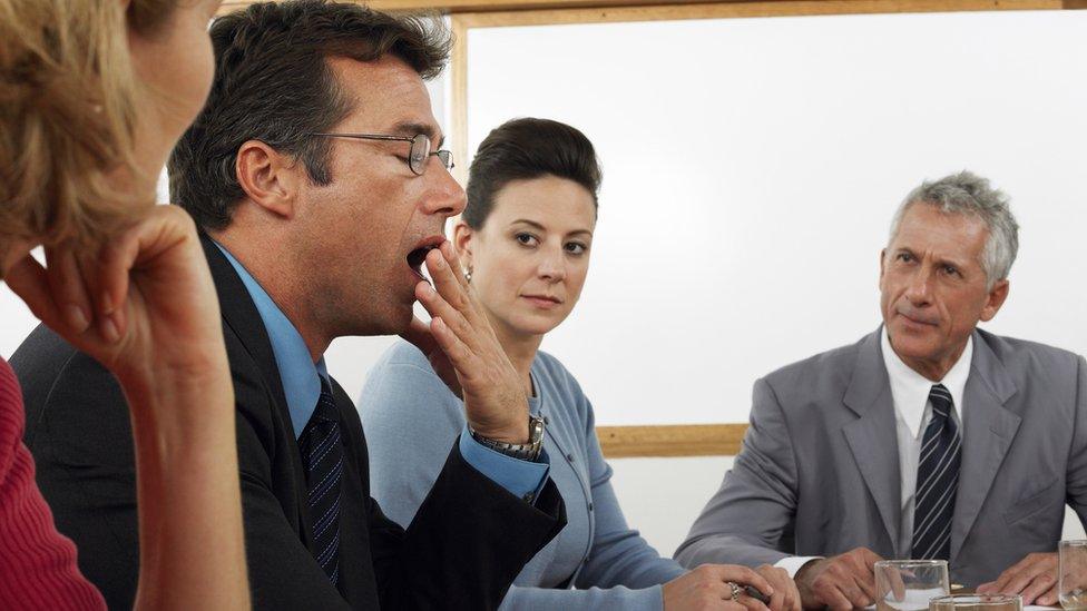 Man yawning in business meeting