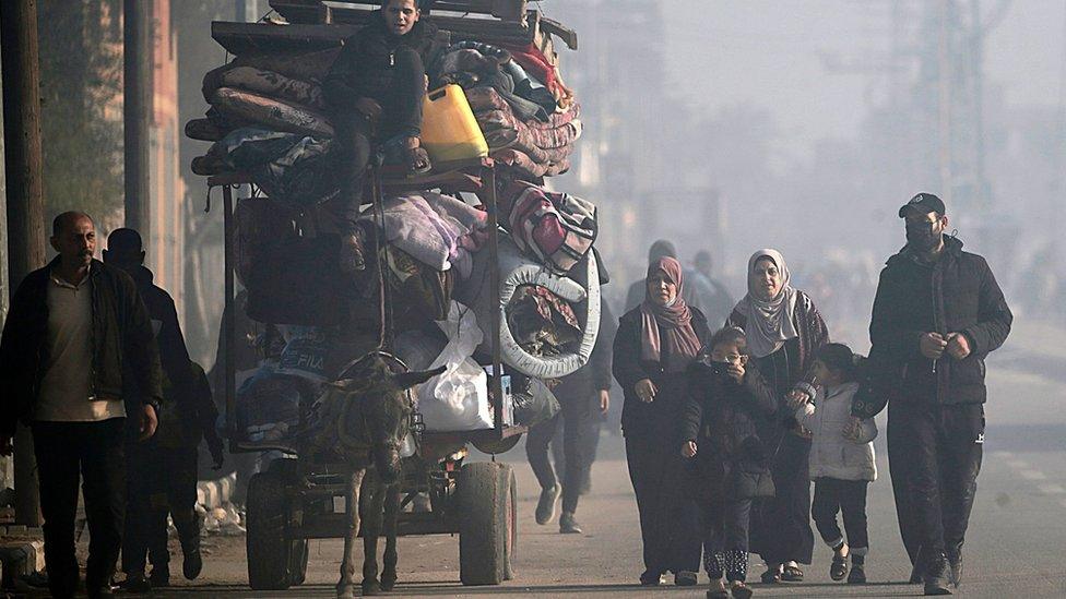 Displaced Palestinians walk along a road after fleeing Bureij, Maghazi and Nuseirat camps in central Gaza (26 December 2023)