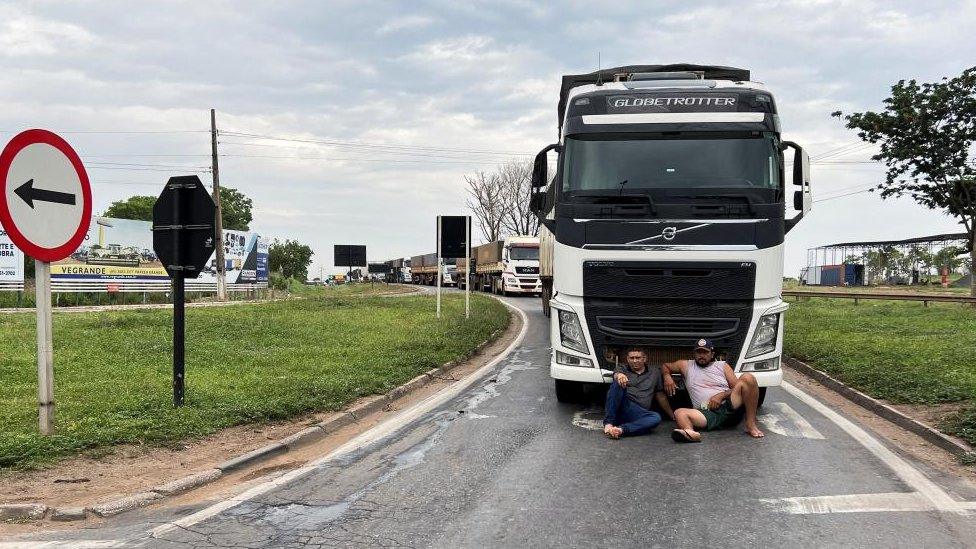 Demonstrators sit in front a truck as they block federal roads during a protest on the day after the Brazilian presidential election run-off, in Varzea Grande in Mato Grosso state, Brazil, October 31, 2022.