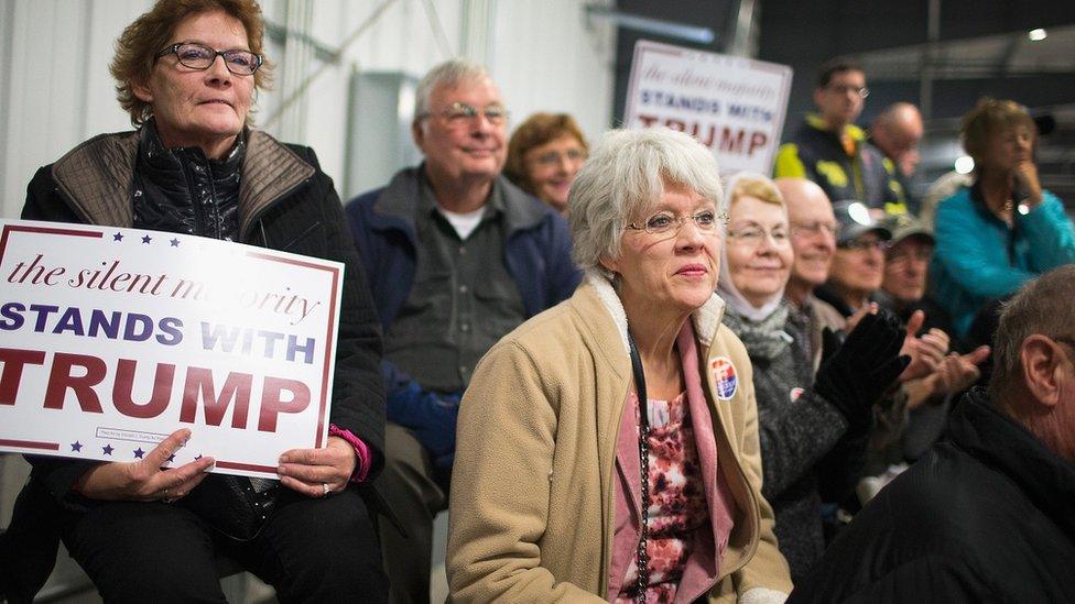 A group of sign-holding supporters listen to Donald Trump speak in Iowa.