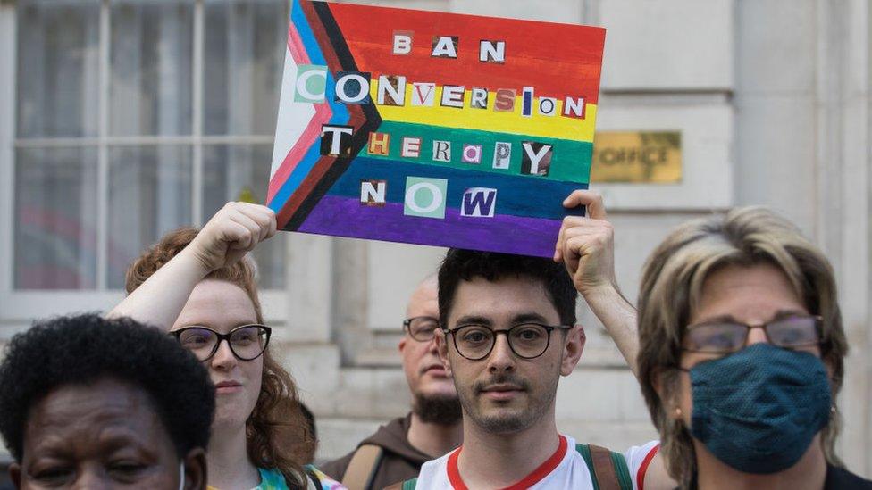 Protesters hold up a sign saying ban conversion therapy