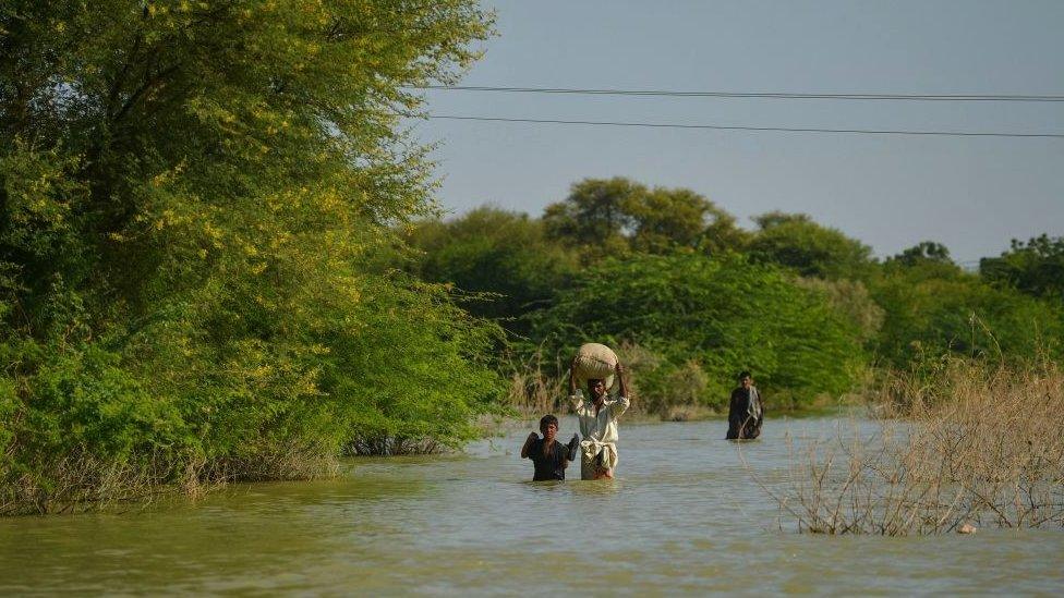 people walking through floodwatr