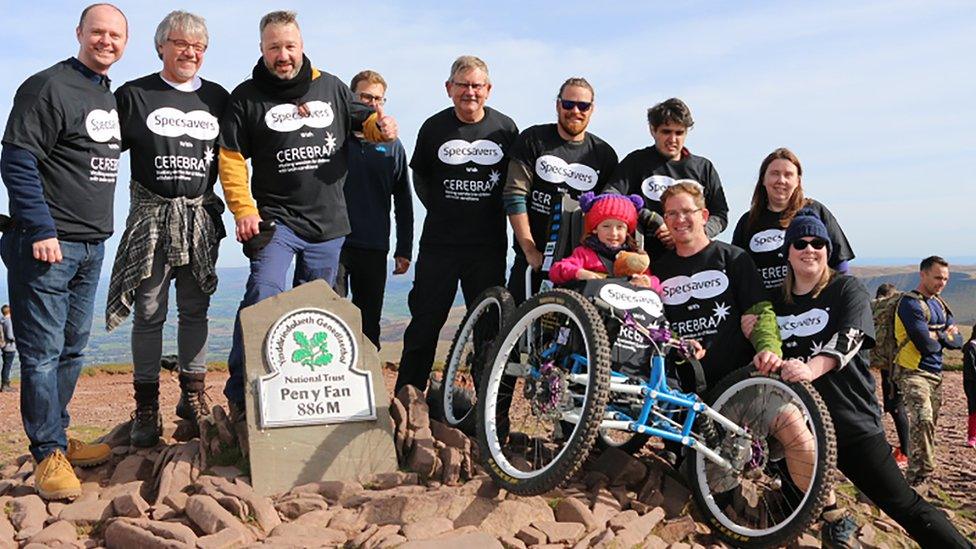 Photo of six-year-old Imogen Ashwell-Lewis who has cerebral palsy got to the top on a four wheeled bike helped by volunteers