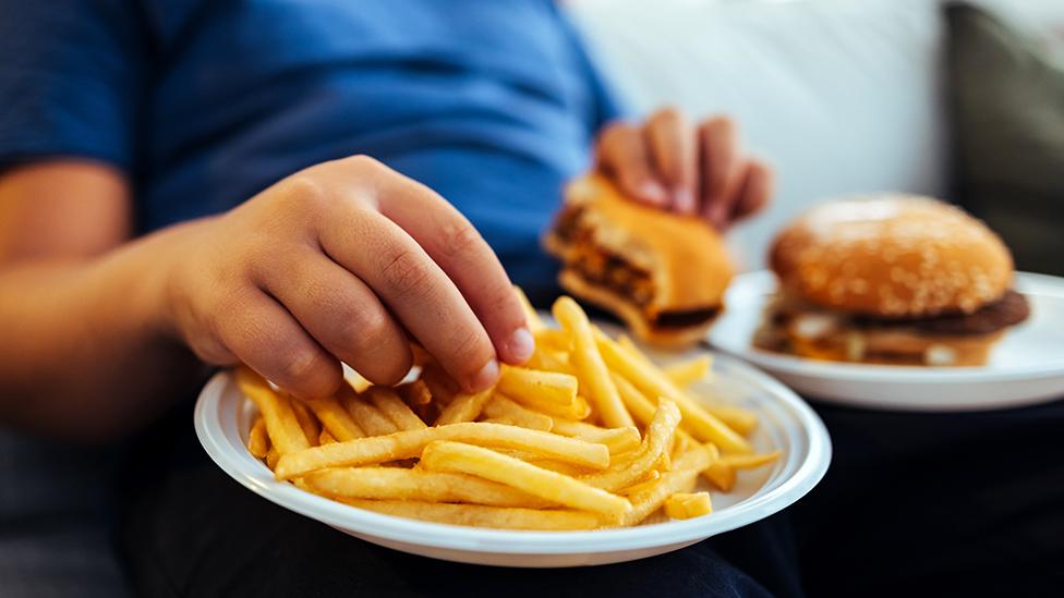 Anonymous child eating burger and chips at home