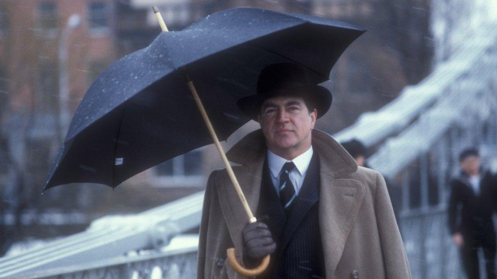 Alan Bates with an umbrella in the rain