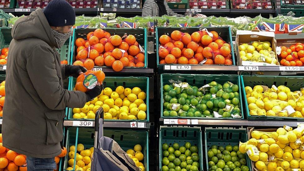 A shopper at a fruit section in a supermarket