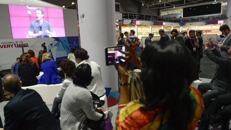 Onlookers at Mobile World Congress watch Mark Zuckerberg's interview via video link