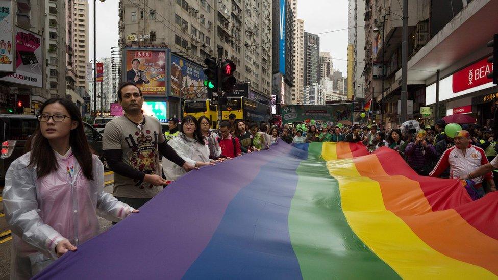 Participants of Hong Kong's annual pride parade walk through the streets with a large rainbow flag on 26 November, 2016