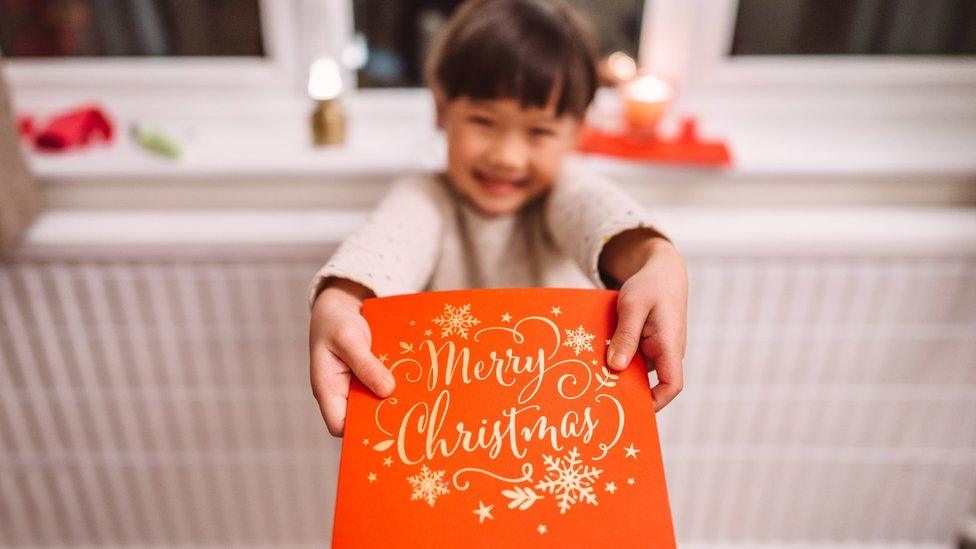 A girl giving a Christmas card to someone