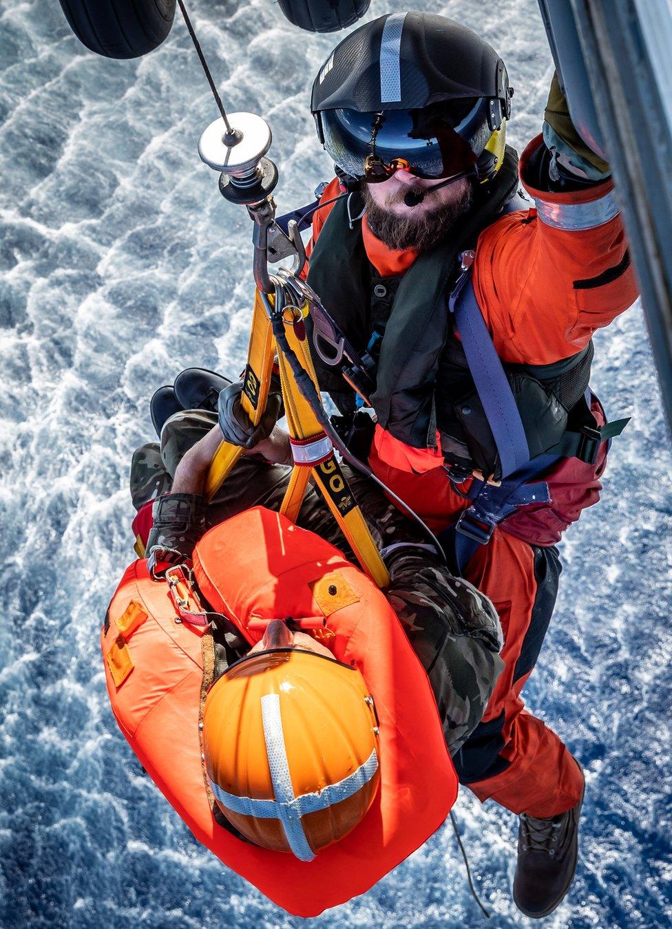 A pilot is winched onto a helicopter from the sea