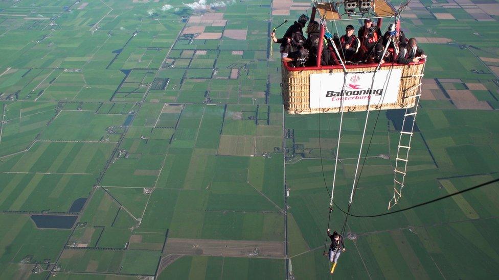 A view of Anna Cochrane suspended below the hot air balloon, which is filled with her support team