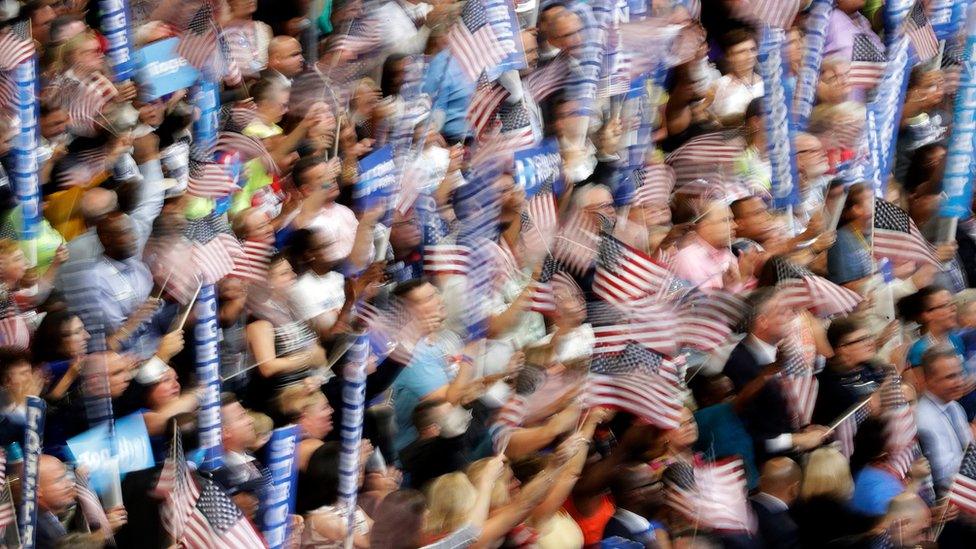 In this photo taken with a slow shutter speed, people wave flags and signs as Democratic presidential nominee Hillary Clinton speaks