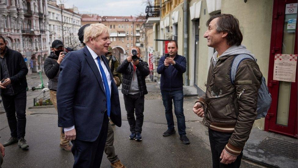 Boris Johnson speaks to a resident during a walk around central Kyiv with President Volodymyr Zelensky