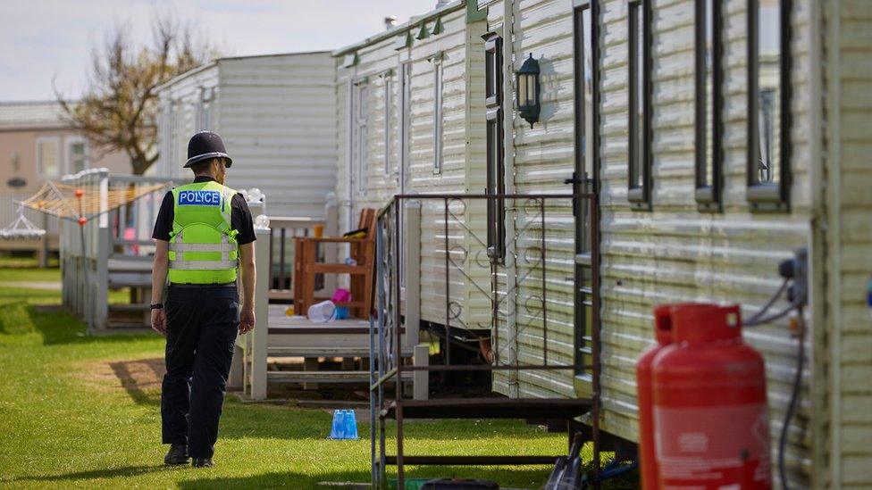 Policeman walking past a caravan