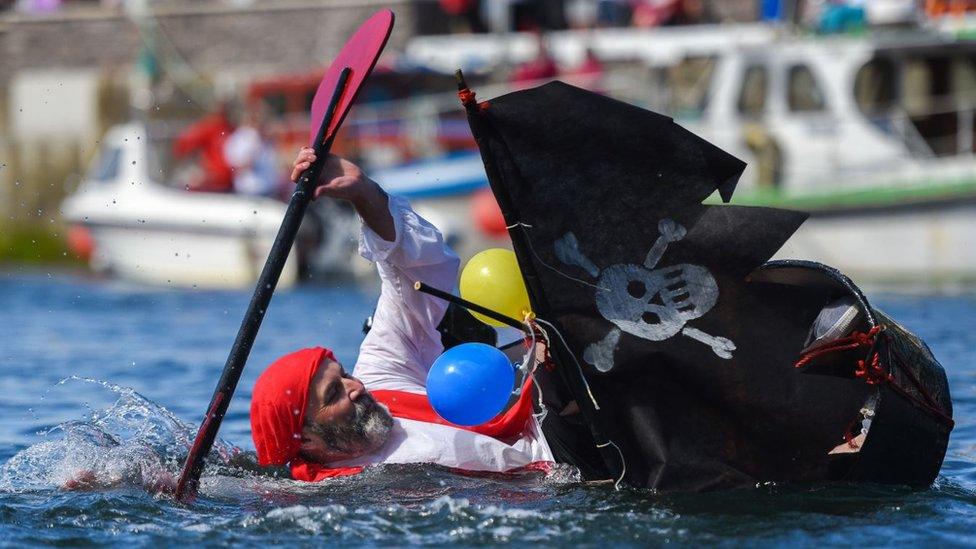 A tin bath races competitor dress as a pirate sinking in Castletown harbour