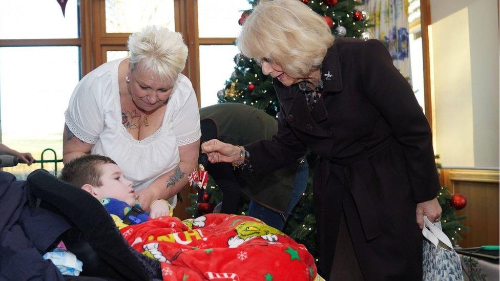 The Queen hands a toy soldier to child