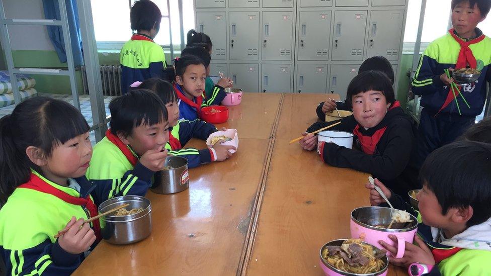 Kids at the school sit around a table eating food