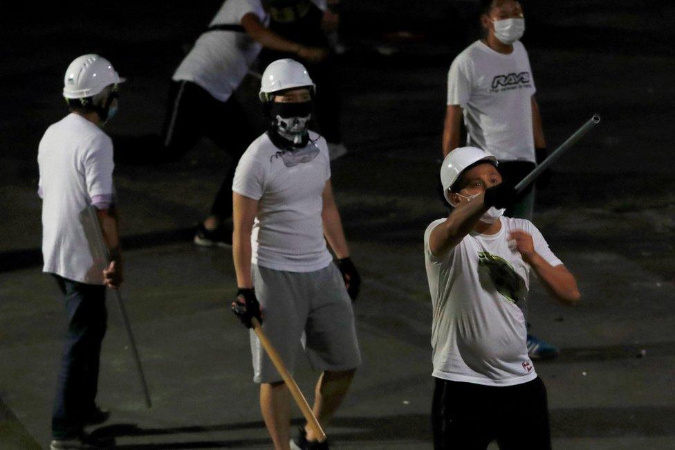 Men in white T-shirts with poles are seen in Yuen Long after attacked anti-extradition bill demonstrators at a train station, in Hong Kong, China July 22, 2019.