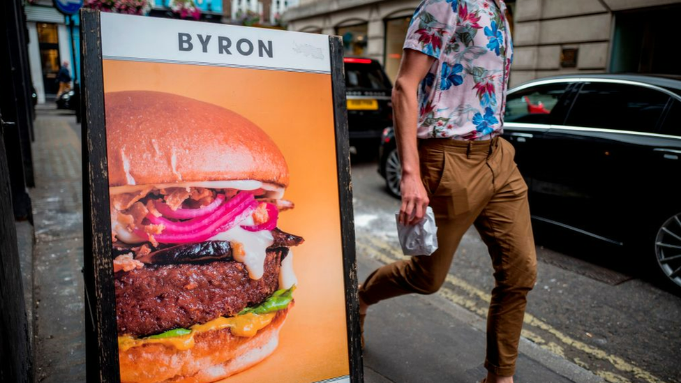 Man walks past Byron Burger sign