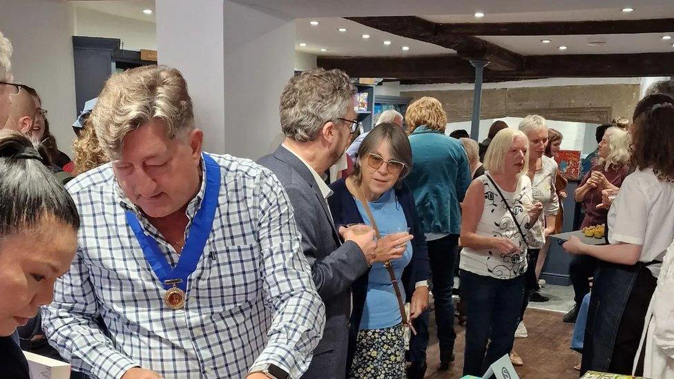 Ground floor of bookshop showing people drinking from glasses and looking at books