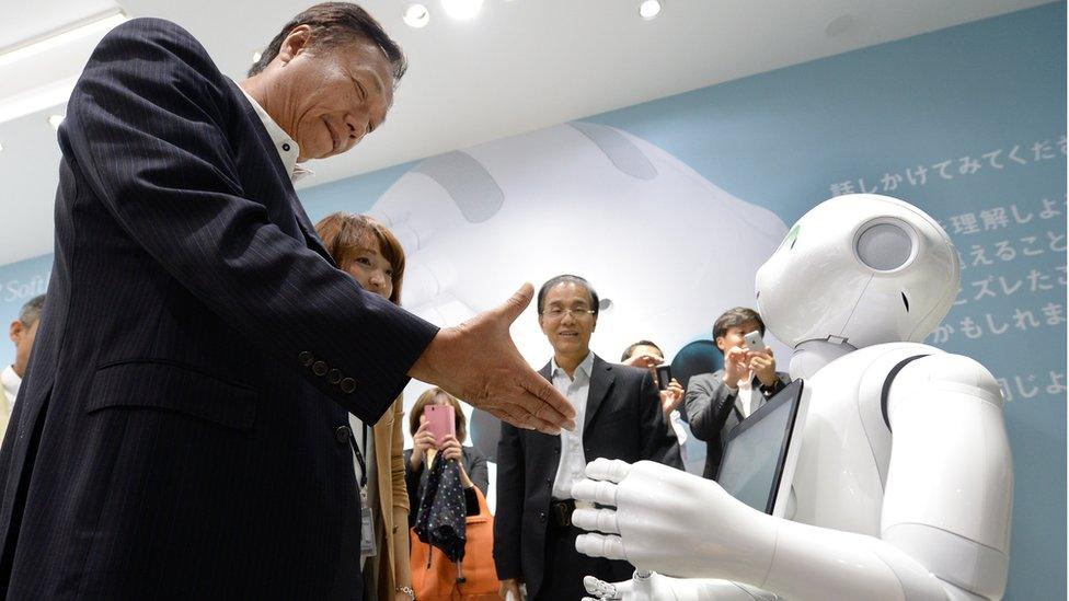 Terry Gou (L), chairman and CEO of Taiwan's Foxconn Technology group, tries to shake hands with humanoid robot 'Pepper' (R), which is jointly developed by Japan's mobile carrier SoftBank and French humanoid robot maker Alderbaran and manufactured by Foxconn, at a showroom of SoftBank in Tokyo, on 6 June 2014.