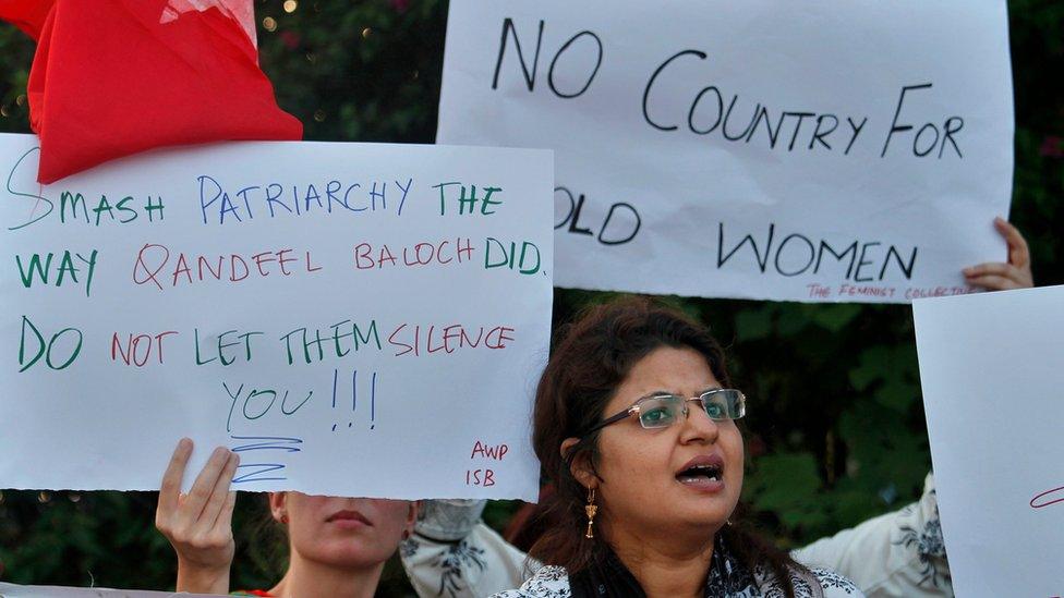 A woman holds a placard saying "no country for old women".=